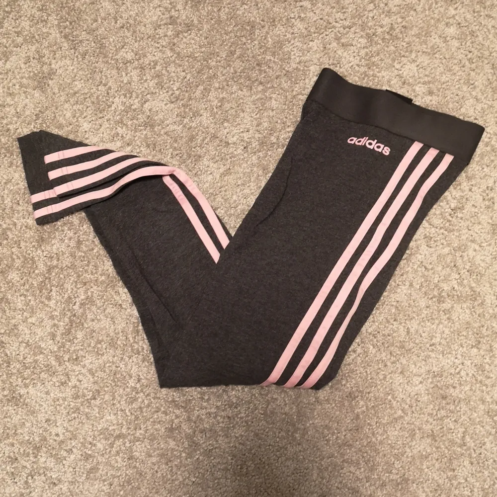 Ett par supersnygga Adidas tights i en mörkgrå färg med rosa streck. Säljer då de blivit för korta för mig. I superbra skick i storlek XS. . Jeans & Byxor.