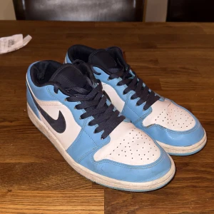 Jordan 1 low unc  - Skorna är creasade och har några sprickor i skinnet och en skada i tyget vid hälen men den känns inte av när man har på sig dom. Skorna leveras i original boxen. Original pris 3200kr Priset är ej fast.