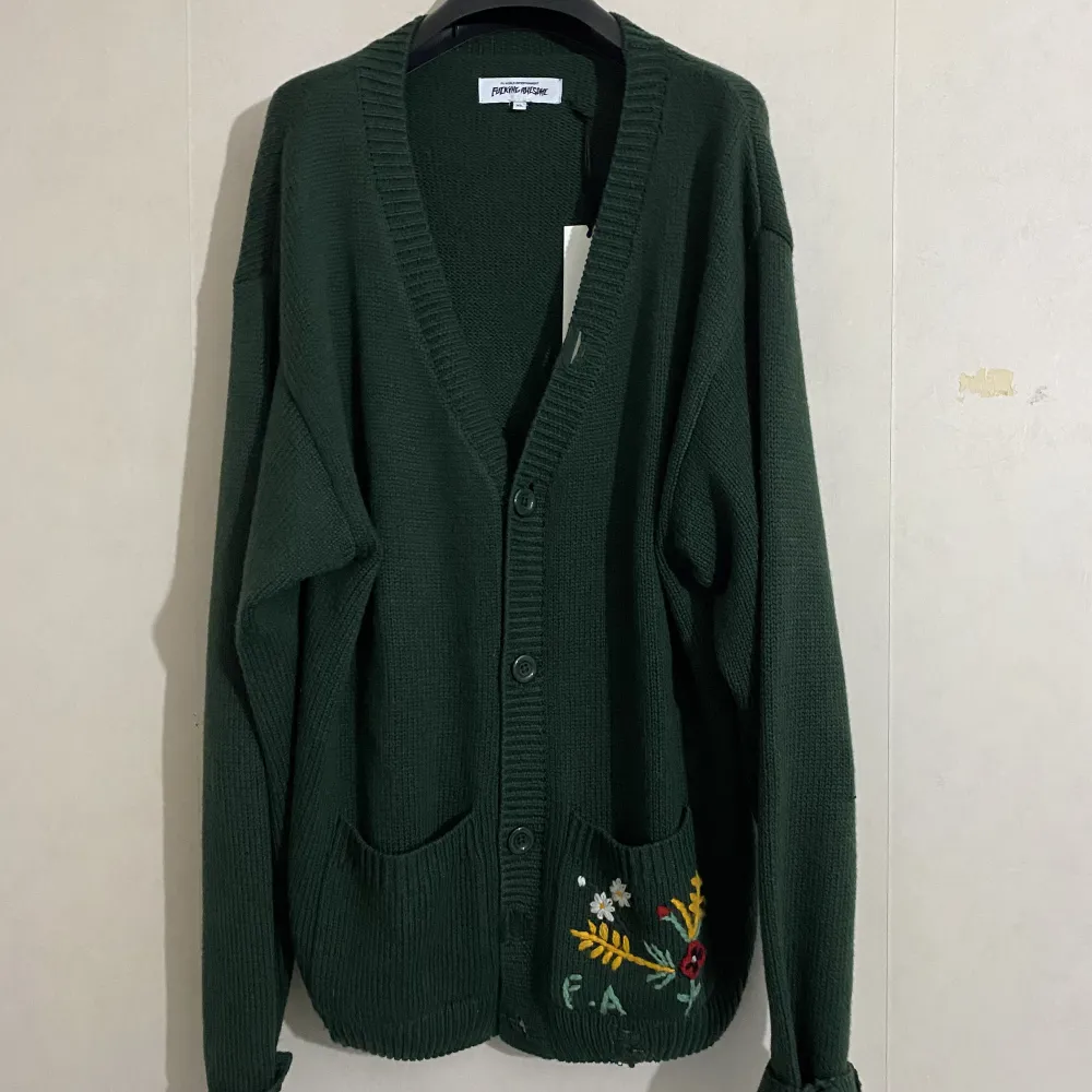 Fucking awesome cardigan XL  Sold out everywhere. Highly sought after piece only worn 2-4 times.  This oversized Fucking Awesome cardigan is knitted from a forest green wool blend. It has small square pockets, one of which is embroidered.. Tröjor & Koftor.
