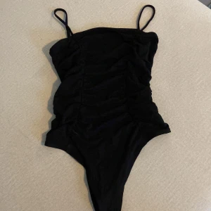 Svart body - Snygg body, dock aldrig använt pga för liten. Superskönt material dock!  Veckad detalj framtill som gör den lite roligare 😊