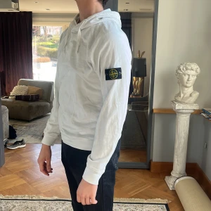 Stone Island Hoodie - vit - En vit Stone Island hoodie, strl L, patchen är i fint skick då jag tagit av den innan varje tvätt, inga fläckar/hål. Tyvärr har jag klippt bort lappen då jag tyckte den störde mig när jag använde hoodien men såklart äkta! Tveka inte på skriva vid undran!