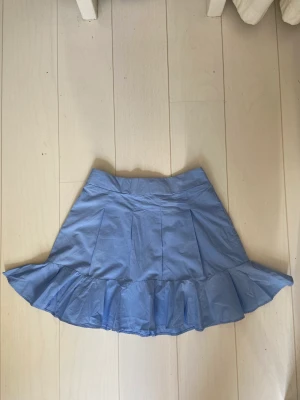 Blå volang kjol - En blå volang/veckad kjol  Använd bara 2 gånger  Den är fin till sommaren  Är storlek S men lite stor på mig i midjan och jag brukar ha S