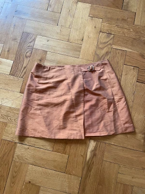 Kjol  - Fin orange kjol. Står storlek 44 men skulle säga att den är storlek 38/40. Går att spänna åt för att göra mer tight. 