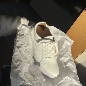 Oanvända vita sneakers  - Jag måste tyvärr sälja dessa sååå fina vita sneakers i läder som tyvärr är för små för mig. Jag hade tänkt ha dem på studenten men kunde tyvärr inte skicka tillbaka dem. De är från märket Noosy och har tyvärr ingen prislapp på sig men är aldrig använda.