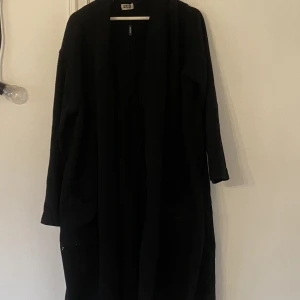 Svart kappa - Vårkappa i svart. 40%polyester 31% viskos 27% ull  2% andra fibrer