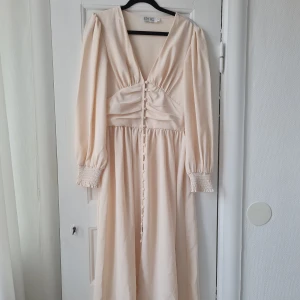 Långklänning - Är aldrig använd, endast struken och provad. Har knappar framtill som kan knäppas upp helt. Älskar denna klänningen men tyvärr är färgen helt fel för mig så hoppas verkligen att någon får användning för den. Nypris 849 kr, köpt på BY IC