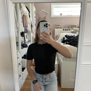 En svart ribbad t-shirt  - En svart ribbad topp från Zara. Med vita volang detaljer.