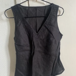 Topp med pärlor - Topp med pärlor och mönster som detalj. Figursydd med V urringning.