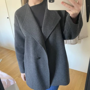 Vårkappa  - Kort mörkgrå kappa, perfekt till våren! Lite nopprig vid ärmarna men går att ta bort med en ullkam