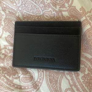 Säljer denna plånbok från Don Donna. Använd ett fåtal gånger men den är som ny. 4 olika fack till kort och ett större fack till sedlar/ kort. Materialet är tyg och fake skinn. 