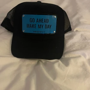 John hatter keps - En keps som jag aldrig haft på mig.  Texten är ’’GO AHEAD MAKE MY DAY’’.