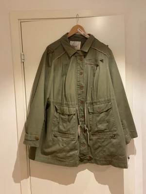 Grön jacka  - Lång grön jacka med massa fickor . Mycket praktisk och man kan sjustera alla möjliga grejer. Säljer då ej används 