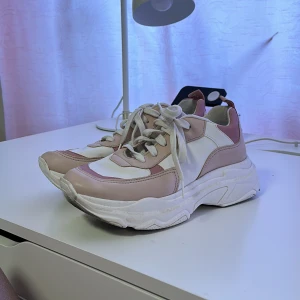 Sneakers med rosa detaljer - Unika sneakers från NAKD med lite uppbyggd sula och detaljer i olika nyanser av rosa. Mycket sparsamt använda men väldigt bekväma. Sulan ser smutsig ut men det är något märkligt med bilden bara. Skickar fler bilder i PM :)