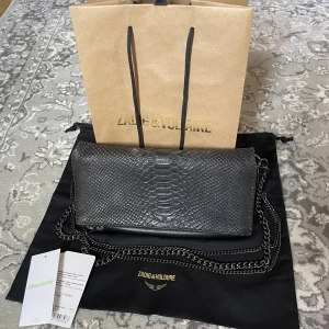 Zadig&voltaire väska - Säljer denna fina väska från Zadig & Voltaire i modellen ” rock clutch”! ❤️‍🔥 Köpt för ca 4000kr och säljer för 2000 (pris kan diskuteras) Dustbag, kvitto och två längder på kedja ingår. Endast naturliga slitningar! 🙌🏽