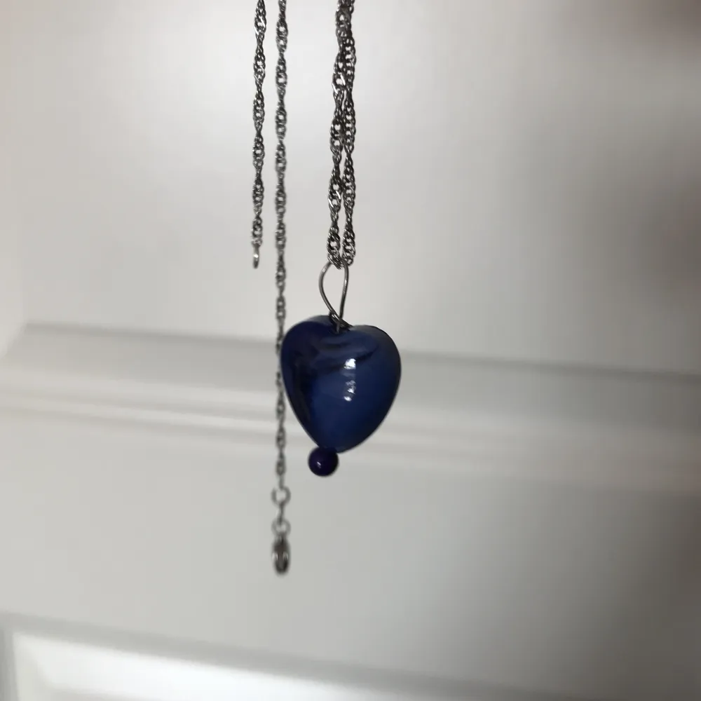Blått halsbandshänge av ett blått glashjärta och fossil sten. Nytt oanvänt och handgjort. Har också andra smycken på min profil🌺. Accessoarer.