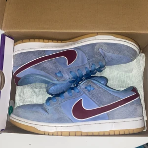 Nike Sb Dunk Low Valor Blue/Team Maroon - Nike Sb Dunk Low Valor Blue/Team Maroon. Storlek 42,5. Nypris på StockX 3500kr. Skick 8,5/10. Priset går att diskutera vid snabb affär. Skriv för mer bilder osv. Box och extra snören i andra färger ingår.
