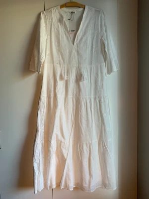 Vit hellång klänning Indiska - Oanvänd med lapparna kvar, 699 kr nypris. Säljer pga ej kommit till användning på hela sommaren.