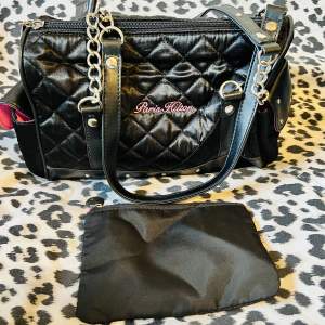 Söt Paris Hilton axel väska.  Mini purse finns i väskan.  Yttre (sido) och inre fack finns.  Färg/ svart, lila.    Ej använd