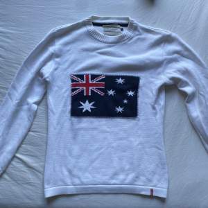 En vit stickad tröja med australienska flaggan på. Syermysig och söt i storlek L.