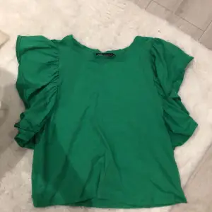 En jättefin grön tröja med volanger från Zara, Tröjan är slutsåld. Har nästan aldrig använts. Tröjan har inga hål eller fläckar💓
