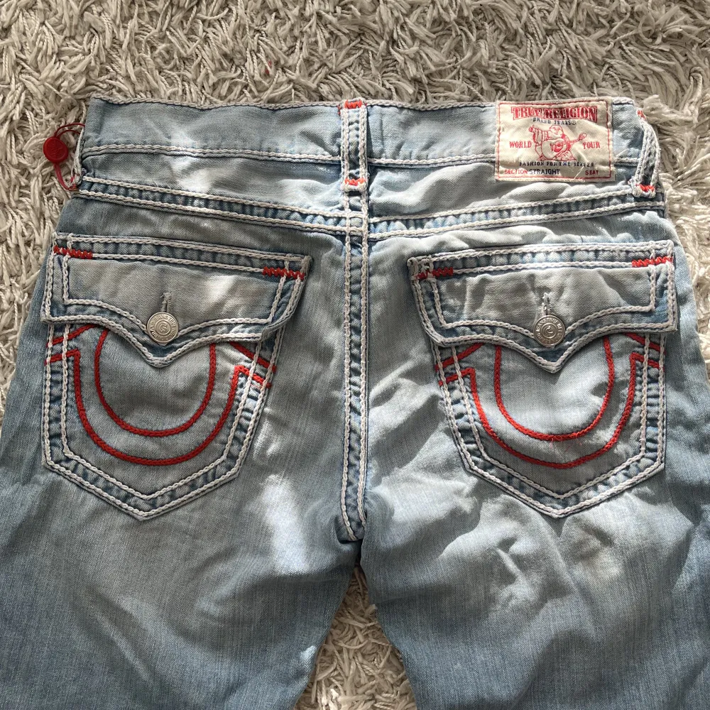 Light washed true religion rope stitch jeans i storlek 34. Vit rope stitch med röd horseshoe bak. Mått: 92cm i midja, 81cm innerbenslängd och 23cm tvärsöver benöppning. Riktigt bra skick endast använda ett fåtal gånger. . Jeans & Byxor.