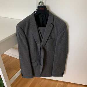 Kostym komplett Hugo Boss - Kompletten består av byxor, kavaj, väst o sen finns det extra knappar i en ficka och en kedja vid en ficka där man stänger.   Det finns ett pris redan Men det går också att diskutera priv och komma fram till bättre pris!   M/L