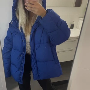 Vinterjacka - En marinblå vinterjacka. Jackan är använd men har inga tydliga tecken på användning. Stor i storleken, skulle säga att den är som en M