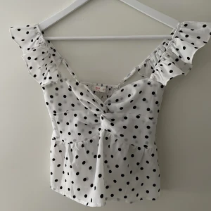 Topp - Söt prickig topp med volanger på banden! Det går att justera banden och är i stlrk S. 