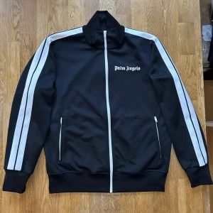 Palm angels zip hoodie - Säljer min Palm angels track top storlek XL.  Skick 9/10 (använd väldigt lite)  Har kvitto på bild ifall de önskas  Kontakta gärna för mer bilder och om ni har frågor  Pris: 2500  Bud från 2100