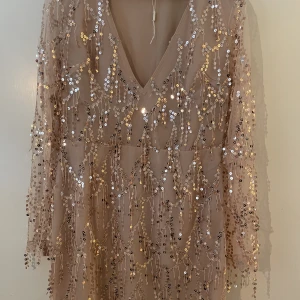 Cocktailklänning - En ljusrosa kort klänning med fina paljetter. Buren endast vid två tillfällen. Passar dig i storlek 38-40