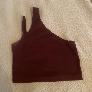 Topp från Weekday - En vinröd topp med en axel