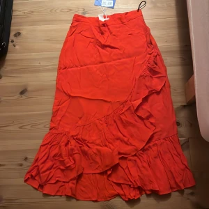 Röd-orange midi kjol - Fin omlott midi-kjol köpt på sellpy för två år sen. Passade mig inte så den är aldrig använd. Storleken är 36 och den är i bra skick. På bilderna är den lite skrynklig, ber om ursäkt