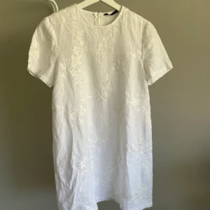 Vit klänning - Jättesöt vit Tshirt-klänning från Zara. Med vita, broderade blommor och dragkedja i bak. Skriv för fler bilder! 