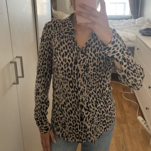 Skjorta i leopardmönster - Skjorta i beigeaktig färg med leopardmönster. Luftig och skönt material. 