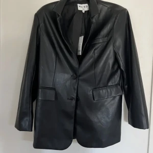 Svart ”skinn kavaj” från nakd - Köpt från Plick. Storlek 36 men passar 34-38 beroende på hur man vill att den ska sitta. 