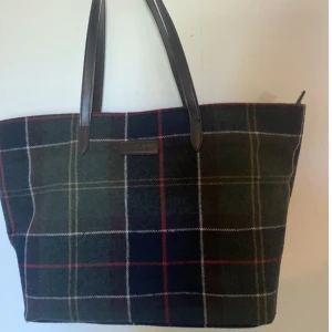 Barbour väska - Väska i filt material från Barbour. Rymlig. Dammig för den stått men aldrig använd:) medföljer en clutch i samma!