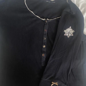 Mörkblå Odd Molly tröja med knappar - Mörkblå Odd Molly tröja med knappar. Så fin och bekväm, med spetsdetalj runt kragen och knappar. Trekvartsärm med rosett, och oddmollymärket på axeln🎀