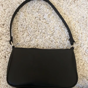 Svart axelväska  - En svart axelväska med små fack i!