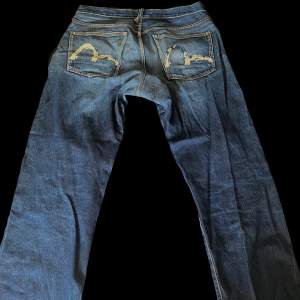 Vintage evisu jeans i hyfsat bra skick, trycket har dock gått bort lite (se bilder) och har lite små märken vid foten. Storlek, midja 40 cm, gylfen till längst ner 79 cm. Skriva gärna innan ni köper