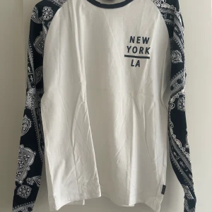 Långärmad tröja  - Långärmad tröja med mönster på ärmarna och tryck över ena sidan av bröstet. Storlek L. Köpt på Jack & Jones för 399kr