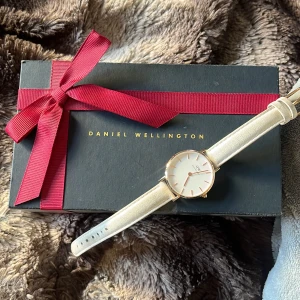 Klocka Daniel Wellington - Säljer min gamla klocka! Guldigt ur men vit läder armband. Går att köpa nytt armband till. Läder armbandet har tappat färg men själv tycker jag att de endast gör klockan snyggare. Skriv privat om ni nar några frågor och prick kan diskuteras ❤️❤️🤗