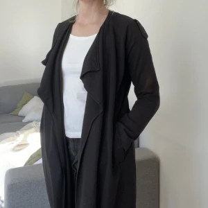 Svart kappa/kofta  - Tunn jacka/kofta i viskos. Perfekt sommarjacka! Passar både XS-M beroende på hur man vill att den ska sitta (jag är storlek 36/38). Har en brun fläck på ärmen. Finns även midjeskärp att fösta runt. 