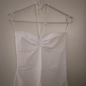 Vit halterneck topp från Gina Tricot, Strlk S-M. NY & OANVÄND. - Vit halterneck topp med knytband i nacken från Gina Tricot, Strlk S-M. (Medium men är mer som Small i storleken enligt mig.) Bomull. NY & OANVÄND. Helt felfri.