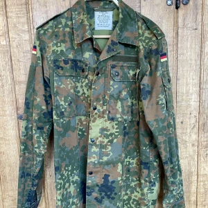 Overshirt / skjortjacka camouflage - En överskjorta eller skjortjacka i camouflage. Blixtlås och tryckknappar. Bra bröstfickor och ärmficka.  Tyska flaggor som går att sprätta bort.Storlek: Small eller liten Medium. Inköpt på en streetwear-butik i Berlin men sen inte använd. Nyskick. 