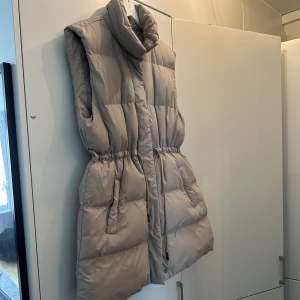 Beige väst  - En oversized beige dum väst i strl 40. Med åtdragbar midja, köptes från stadium och är meningen att vara oversized. Jätte fin på!