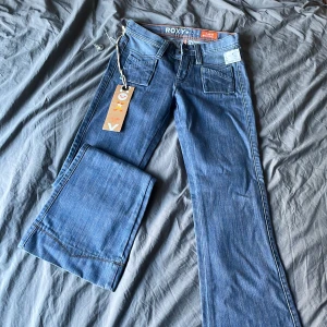 Roxy low rise flared jeans - Helt nya med prislapp kvar.   Sitter som 32 i storleken Midjemått: 79cm Innerbenslängd: 83   Y2k grunge Paris Hilton Britney Spears fairy mcbling rhinestones true religion miss me jeans bootcut flare 2000s 00s 90s 