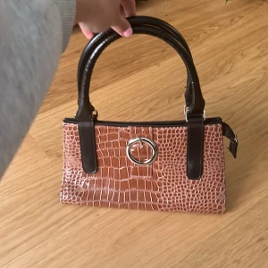 Väska  - Handväska i glansigt material. Knöpt secondhand men aldrig använt.