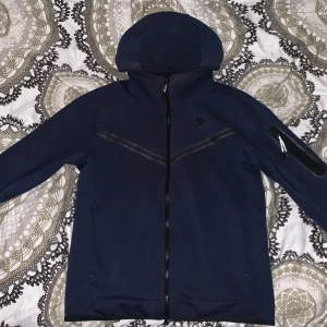Nike tech Fleece Kofta  - Marin Blå Nike tech kofta i bra kondition bara att luvan är solbränd fast bara på insidan och lite utsidan men syns inte om man har på sig den med full zip. Storlek S och pris kan diskuteras 