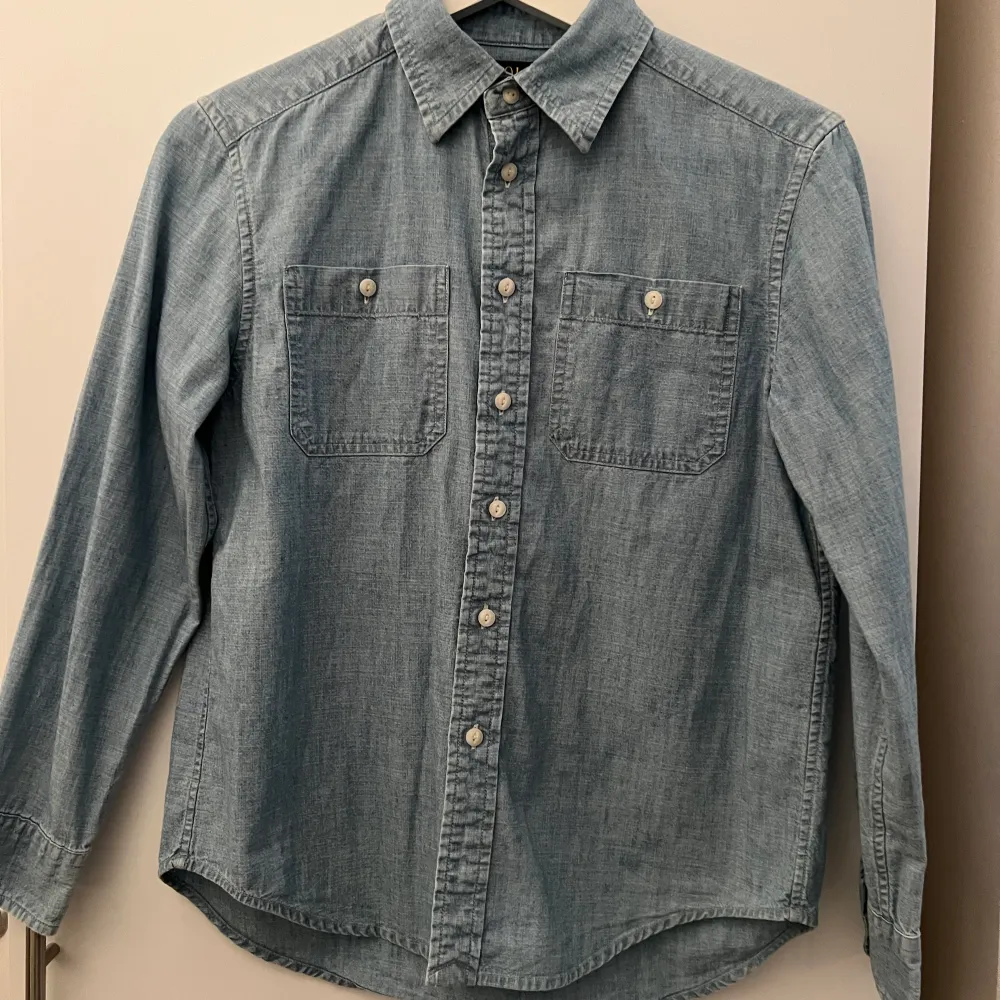 Denna blåa och finna  skjorta är i bra skick men har ett litet håll som ni ser på bilden. Normala pris 995 men säljer för ändas 400kr.. Skjortor.