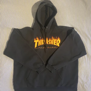 Svart Thrasher Hoodie Flame - Boxy fit. Har använts lite, är i gott skick. Enda skavankerna är tråden som sticker ut från snöret och små sprickor i trycket.